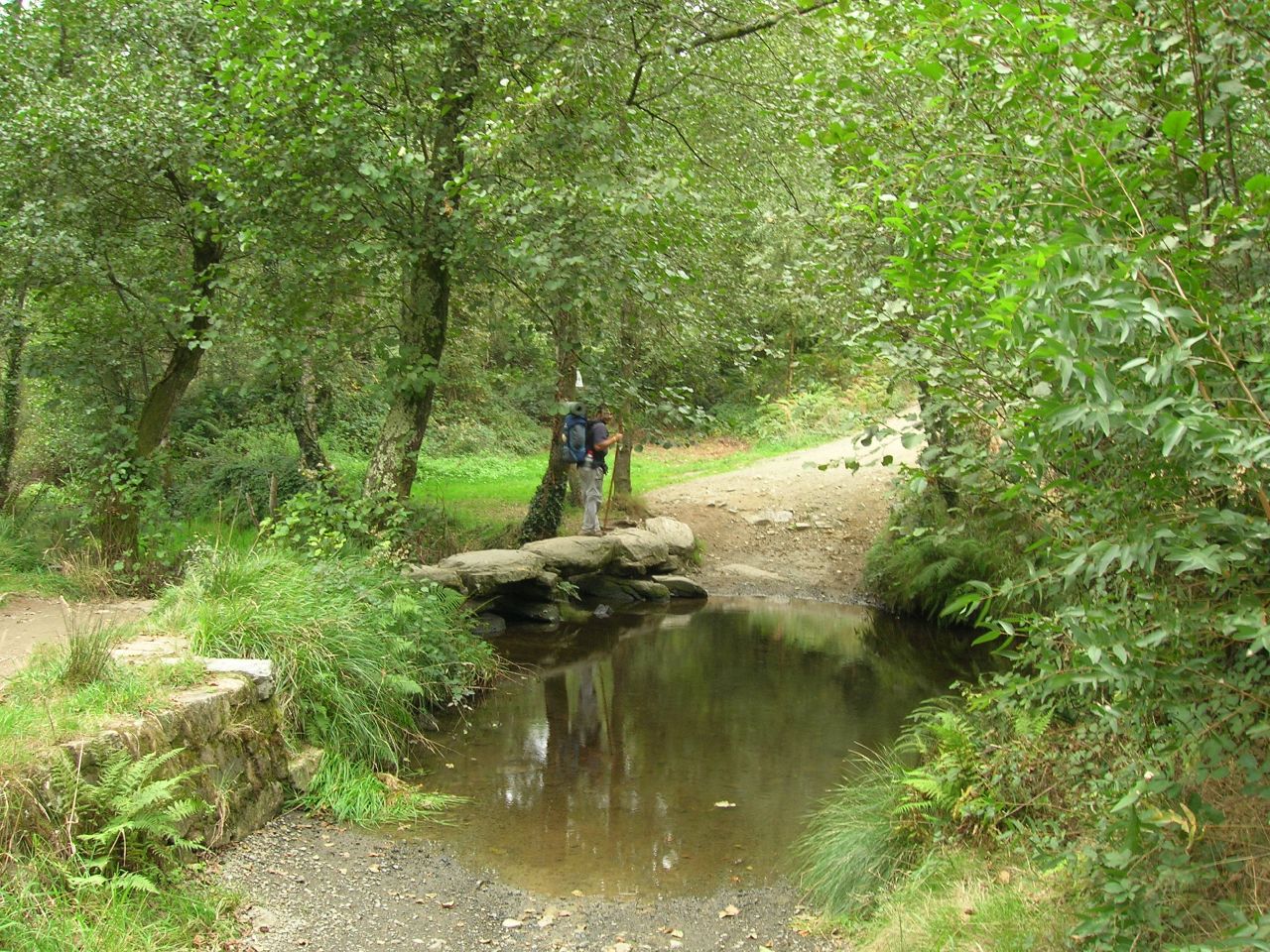 Peregrino siguiendo el sendero sobre el río Catasol, en Melide